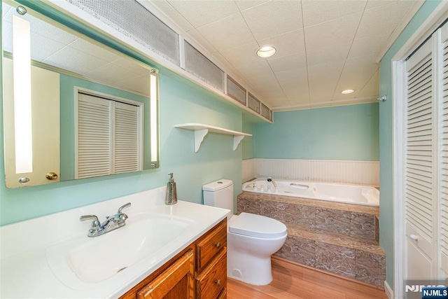 full bath with vanity, a bath, a closet, and wood finished floors