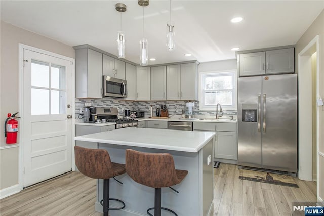 kitchen featuring a sink, gray cabinets, light wood-style flooring, and appliances with stainless steel finishes