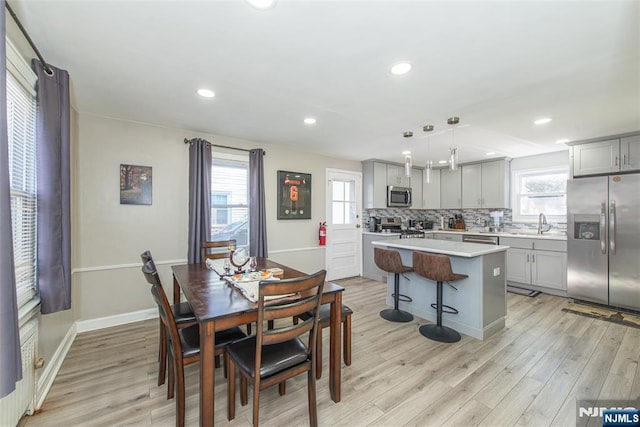 dining room featuring light wood finished floors, baseboards, and recessed lighting