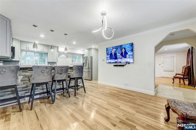 kitchen featuring stainless steel appliances, a breakfast bar area, a peninsula, ornamental molding, and arched walkways