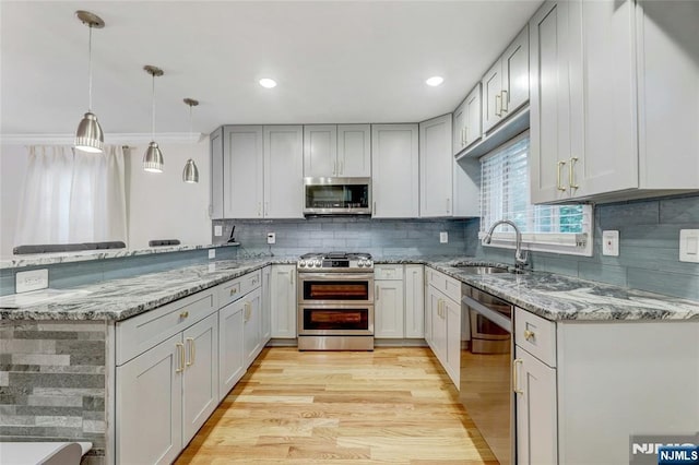 kitchen featuring appliances with stainless steel finishes, a sink, a peninsula, light stone countertops, and recessed lighting