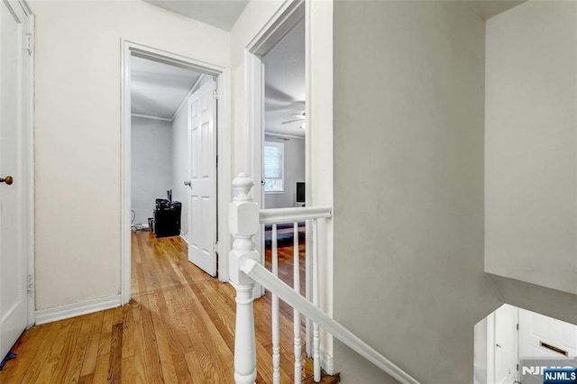 corridor featuring an upstairs landing, light wood finished floors, and baseboards