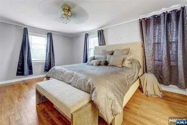 bedroom featuring wood finished floors, baseboards, crown molding, and a ceiling fan