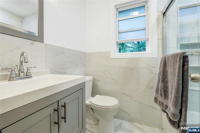 full bathroom with tile walls, marble finish floors, a marble finish shower, toilet, and vanity