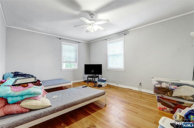 bedroom featuring wood finished floors, ornamental molding, baseboards, and ceiling fan