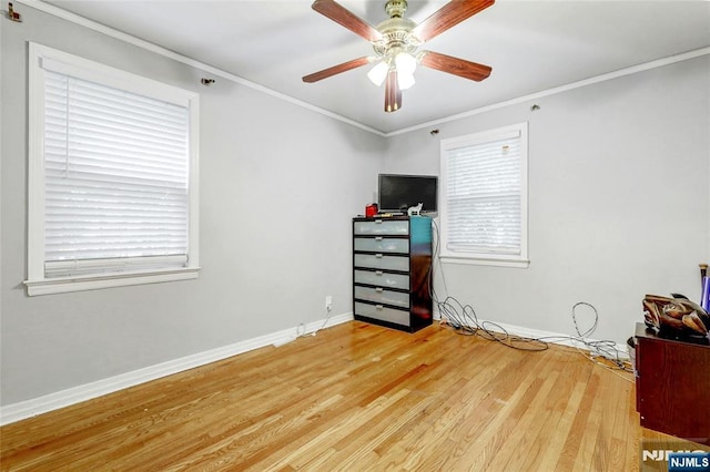 bedroom featuring wood finished floors, multiple windows, ornamental molding, baseboards, and a ceiling fan