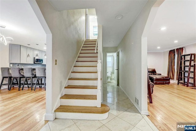 stairs with baseboards, recessed lighting, and wood finished floors