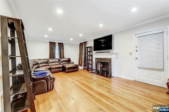 living room with wood finished floors, crown molding, recessed lighting, and a fireplace with flush hearth
