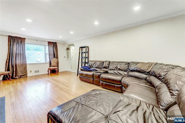 living room with crown molding, light wood-type flooring, recessed lighting, arched walkways, and baseboards