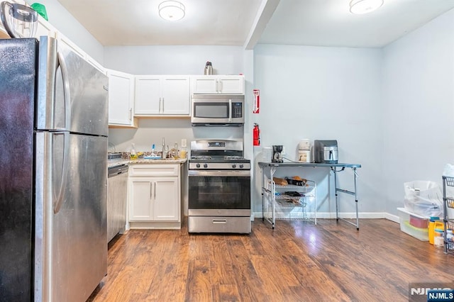 110 Montgomery St, Paterson, NJ 07501 - kitchen with stainless steel appliances, dark wood-type flooring, white cabinetry, and baseboards