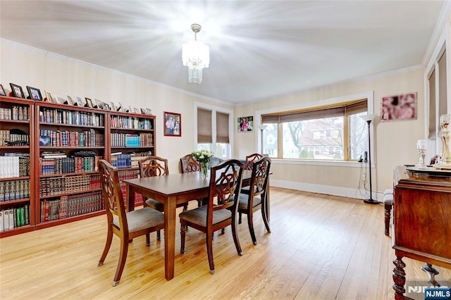 dining space with a chandelier, crown molding, light wood finished floors, and baseboards