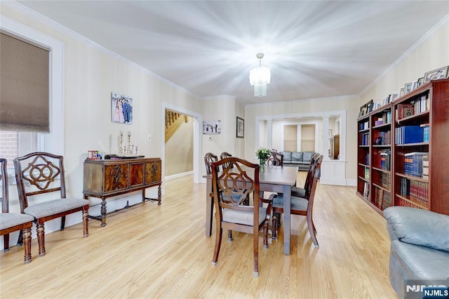 dining area with light wood-type flooring, a chandelier, and crown molding