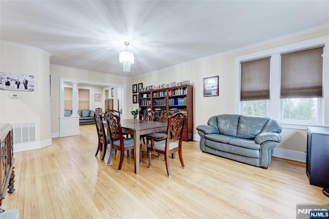 dining space featuring a chandelier, light wood-type flooring, visible vents, and ornamental molding