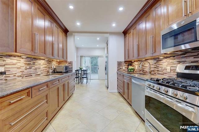 kitchen featuring recessed lighting, appliances with stainless steel finishes, light stone counters, and a sink