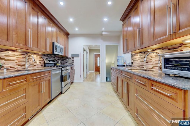 kitchen with baseboards, a sink, recessed lighting, and appliances with stainless steel finishes