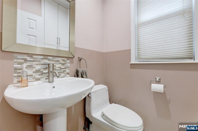 bathroom featuring toilet, a sink, and tasteful backsplash
