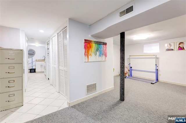 hall with light carpet, baseboards, visible vents, and light tile patterned flooring