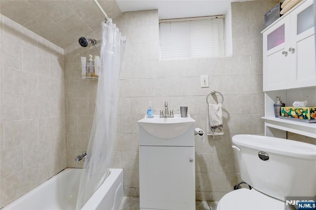 full bath featuring shower / tub combo, toilet, a sink, and tile walls