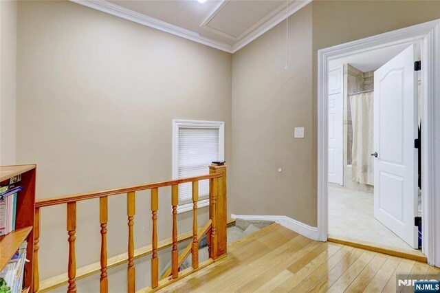 hall with wood finished floors, an upstairs landing, crown molding, baseboards, and attic access