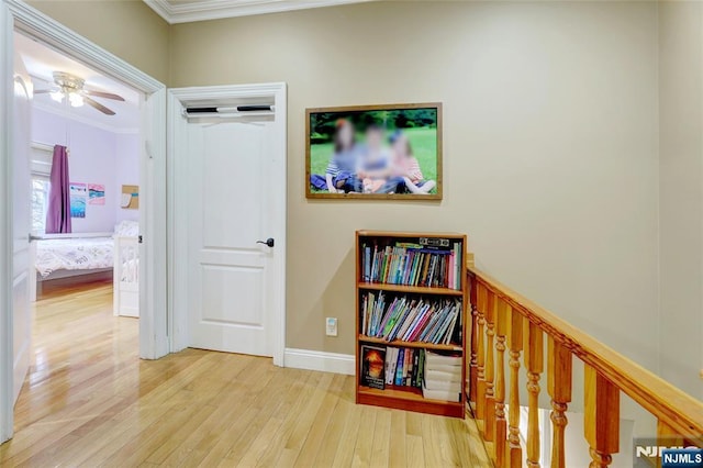 hall featuring an upstairs landing, baseboards, ornamental molding, and wood finished floors