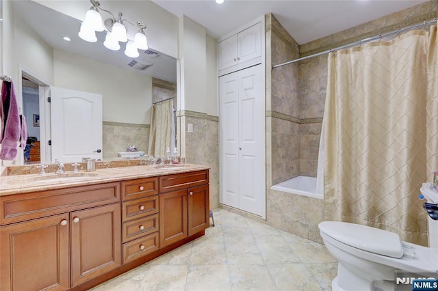 bathroom featuring tiled shower / bath combo, double vanity, toilet, and a sink
