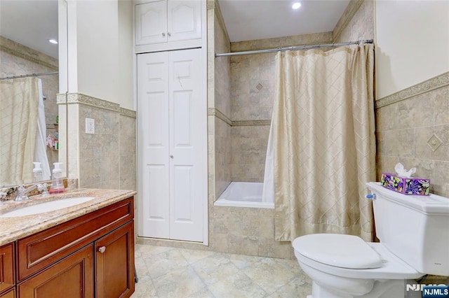bathroom with tiled shower / bath, tile walls, toilet, and vanity