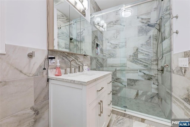 full bath with a shower stall, vanity, and tile walls