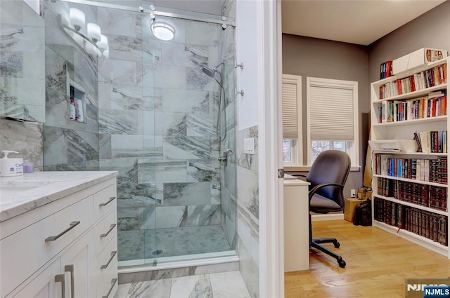 bathroom featuring wood finished floors, vanity, and a stall shower