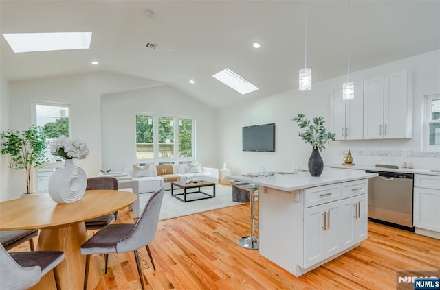 kitchen with open floor plan, light wood-style floors, a kitchen bar, and dishwasher