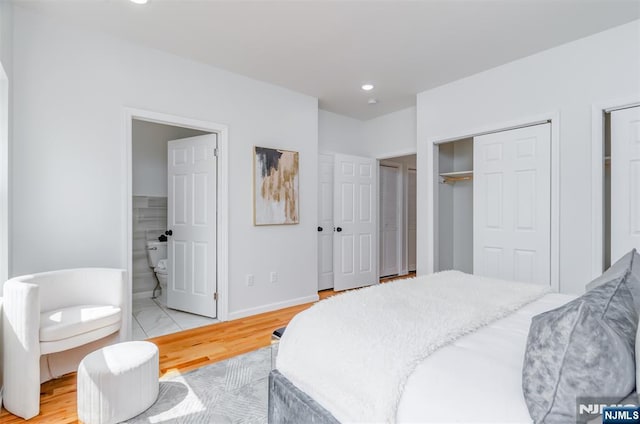 bedroom with baseboards, multiple closets, recessed lighting, ensuite bath, and light wood-style flooring