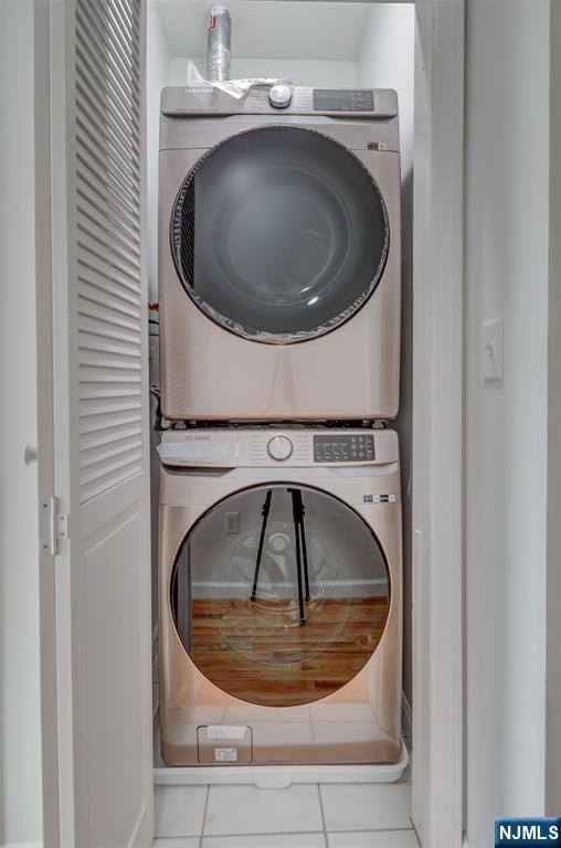 washroom with tile patterned floors, stacked washing maching and dryer, and laundry area