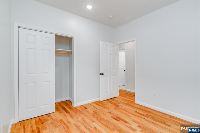 unfurnished bedroom featuring a closet, recessed lighting, light wood finished floors, and baseboards