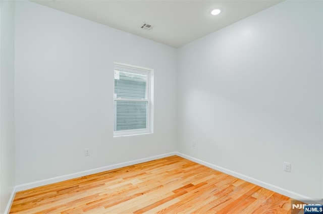 empty room featuring wood finished floors, baseboards, visible vents, and recessed lighting