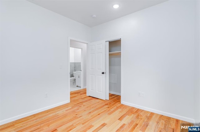 unfurnished bedroom featuring light wood-type flooring, a closet, baseboards, and recessed lighting
