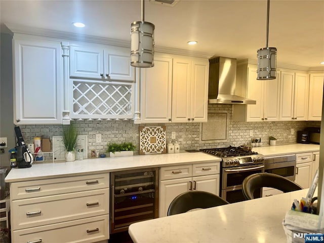 kitchen featuring beverage cooler, wall chimney range hood, double oven range, light countertops, and recessed lighting