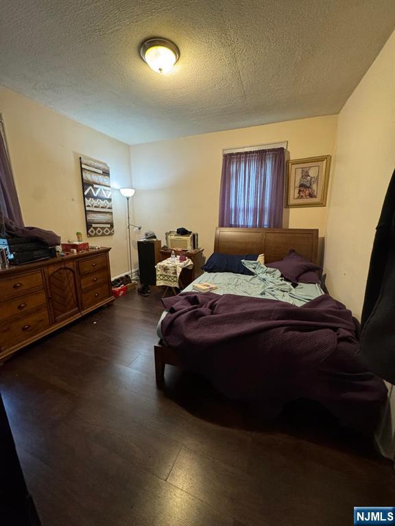 bedroom with dark wood-style floors and a textured ceiling