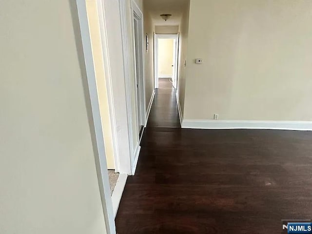corridor with baseboards and dark wood-style flooring