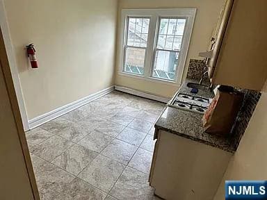 kitchen featuring stone countertops, baseboards, stainless steel gas cooktop, and a sink