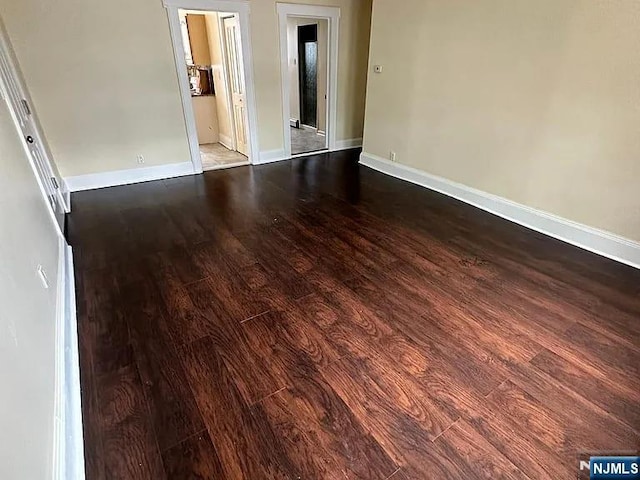 empty room featuring baseboards and dark wood-style floors