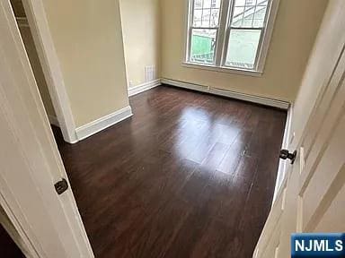 spare room featuring baseboards and dark wood-style floors