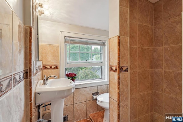 full bathroom featuring toilet, tile walls, and a tile shower