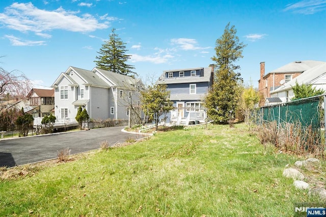 view of yard with fence, a residential view, and driveway