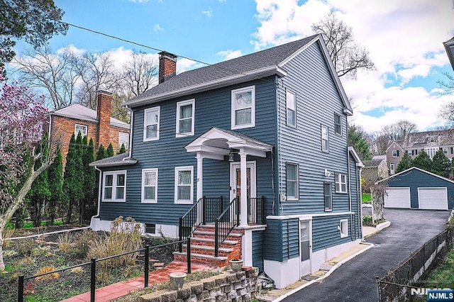 view of front of home featuring fence, an outdoor structure, a garage, and a chimney