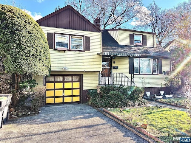 view of front of house with a garage, aphalt driveway, and a chimney