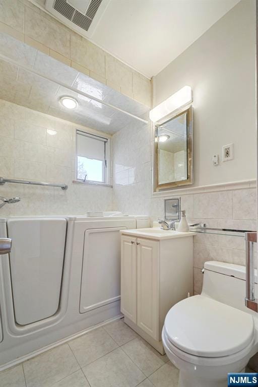 bathroom with visible vents, tile walls, tile patterned flooring, vanity, and toilet