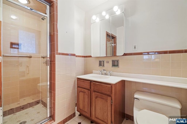 bathroom with vanity, tile walls, a stall shower, and toilet