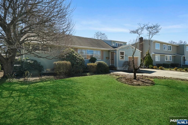 view of front facade featuring a garage, a front lawn, and concrete driveway