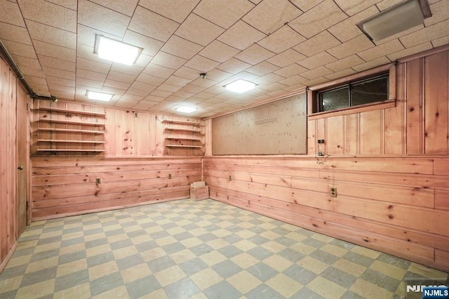 finished below grade area with wood walls, tile patterned floors, and built in shelves