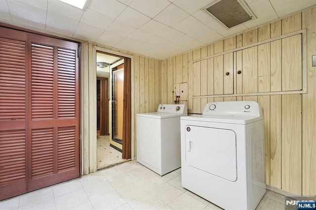 washroom with light floors, laundry area, wood walls, and independent washer and dryer
