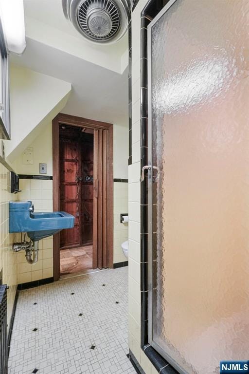 bathroom with tile walls, a stall shower, and toilet